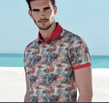 A man in a red-collared floral print polo shirt on a beach