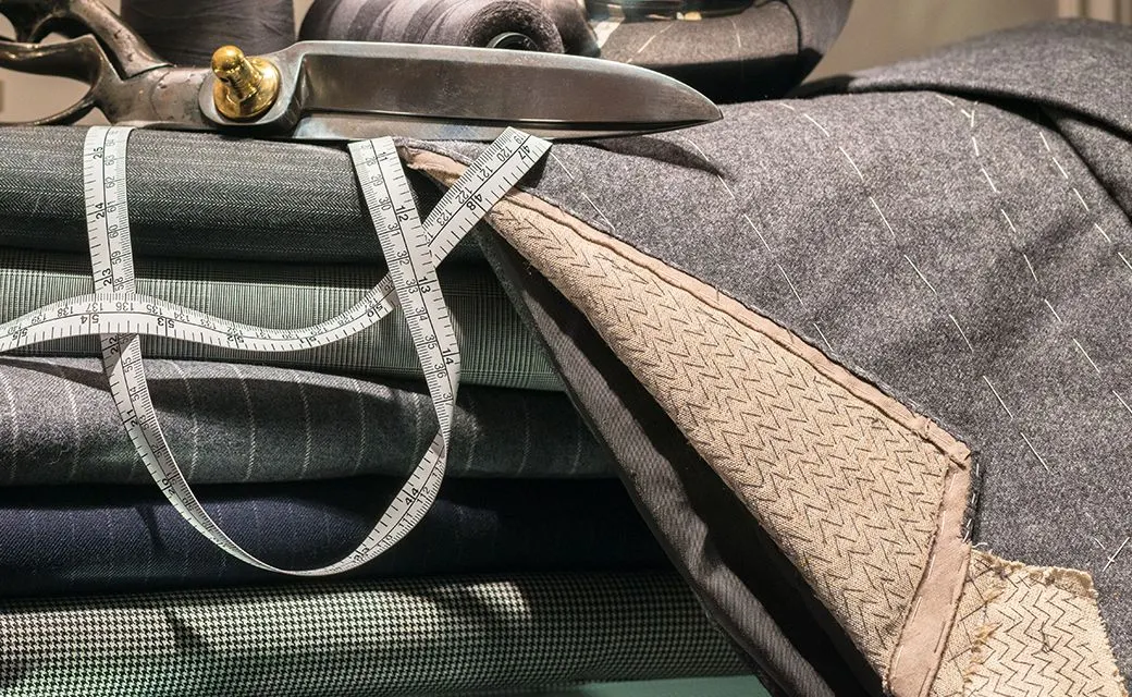 Tailor's shears and a measuring tape resting on folded suiting fabric